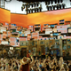 A Coachella crowd waves their arms in the air in front of a colorful stage set for artist Anitta.